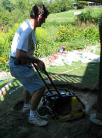 Tim uses vibrating plate compactor to prepare patio